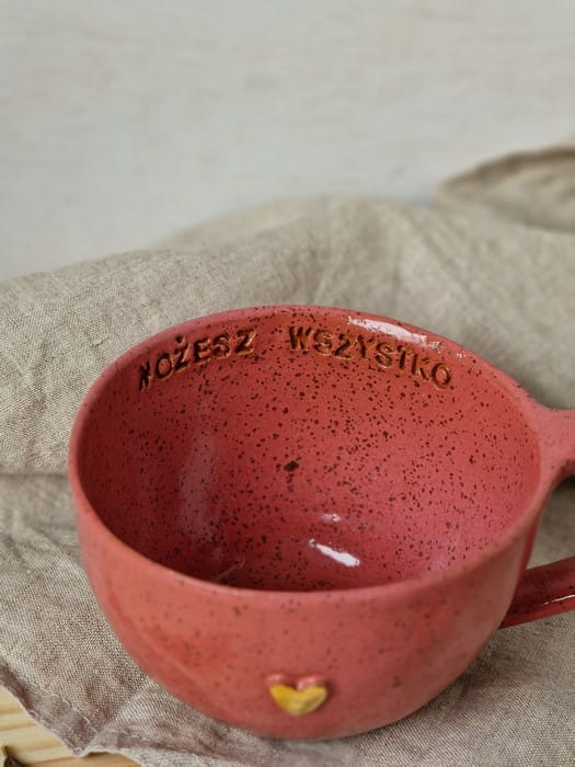 Ręcznie robiona filiżanka ceramiczna 300 ml w kolorze malinowym na stole