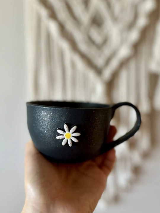 Filiżanka ceramiczna z kwiatem 300 ml czarna trzymana w dłoni handmade