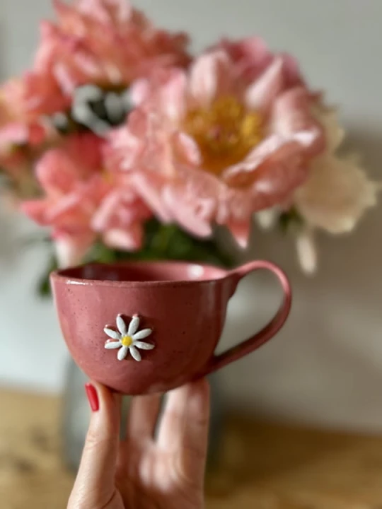 Filiżanka ceramiczna z kwiatem 300 ml malinowa trzymana w dłoni handmade