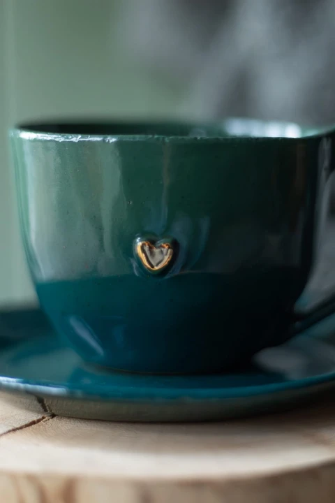 Zbliżenie na szkliwo i złote zdobienie zielono-morskiego kubka ceramicznego handmade