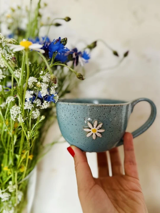 Filiżanka ceramiczna z kwiatem 300 ml turkusowa trzymana w dłoni handmade