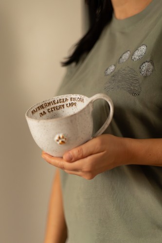 Kubek ceramiczny 400 ml stracciatella ze złotą łapką i afirmacją trzymany w dłoni